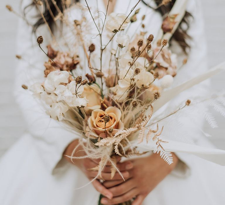 Dried flower bouquet of roses and wild grasses for minimal all white wedding