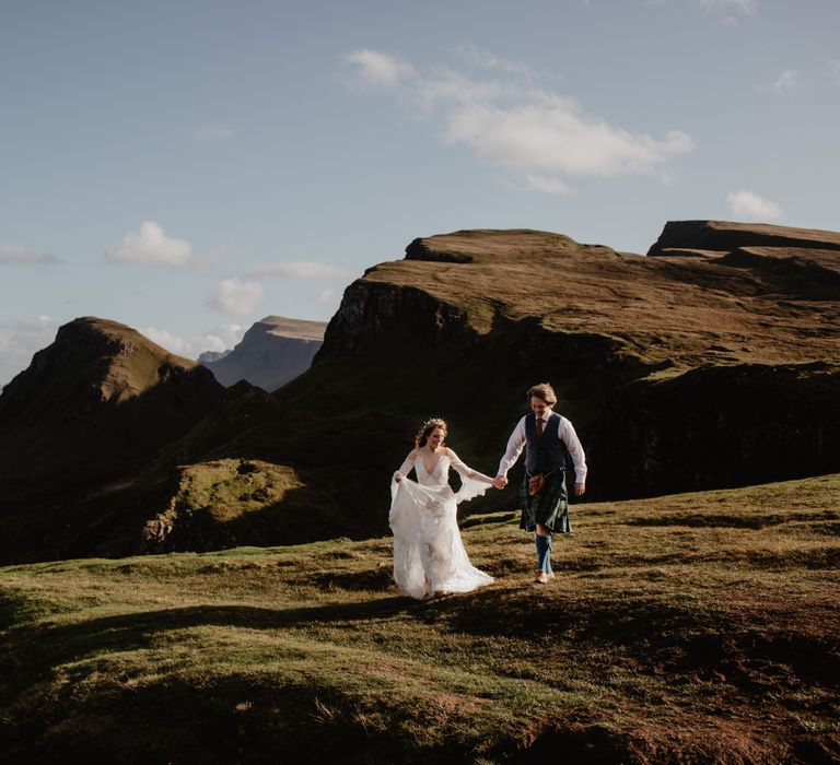 Bride & groom walk across the hillside in the Isle Of Skye