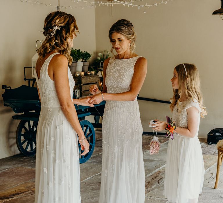 Brides during wedding ceremony exchange wedding rings as daughter looks on 