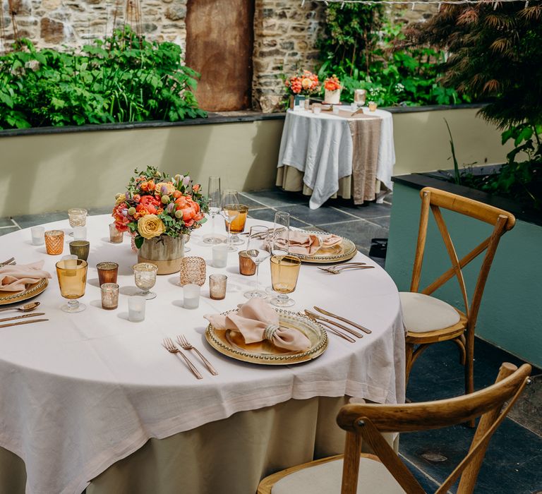 Wedding reception tablescape complete with gold plates and rustic pale pink napkins