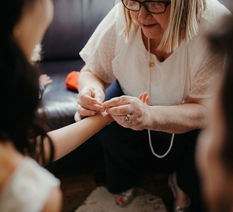 Mother of the groom fastening a bracelet on the bride's wrist