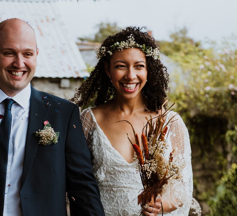 Bride & groom smile with one another as they walk along together in Cornwall 