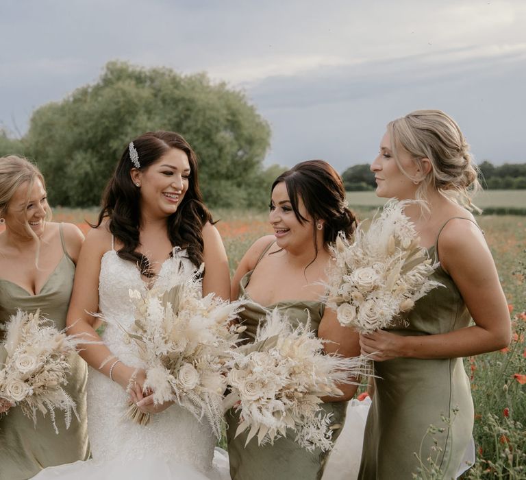 Bride and bridesmaids standing in a poppy field holding dried flower bouquets 