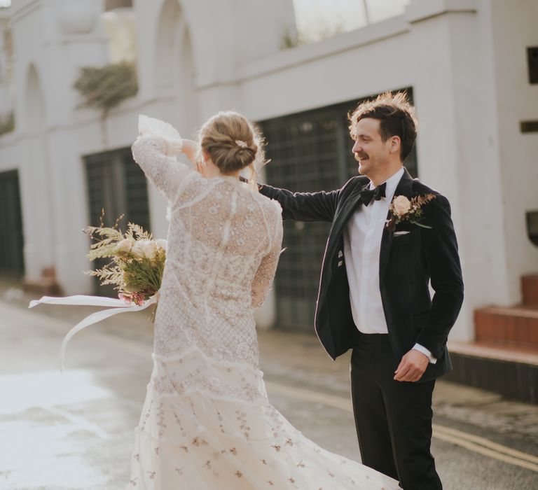 Groom spins his bride around as they dance in the streets on their wedding day