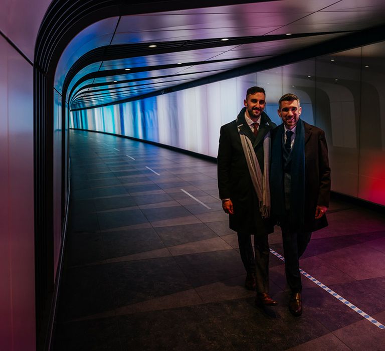 Grooms walk through multicoloured walkway in train station 