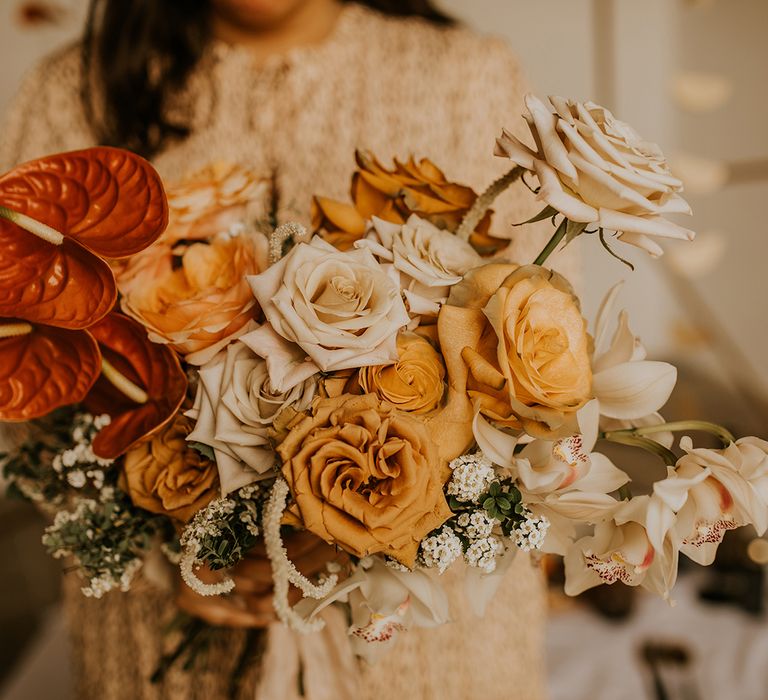 Wedding bouquet with orange anthuriums, yellow roses and foliage 