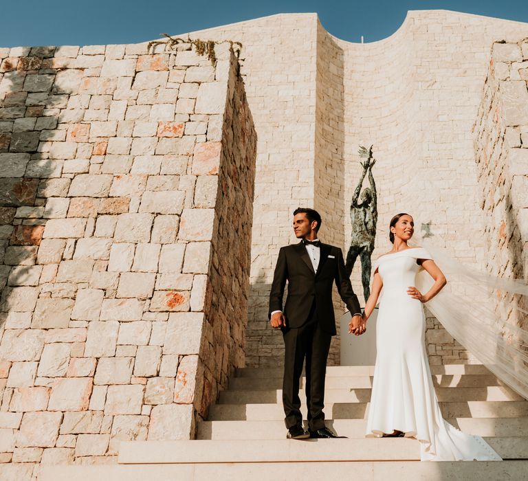 Bride & groom pose in front of white brick walls on their wedding day | Hannah MacGregor Photo & Film