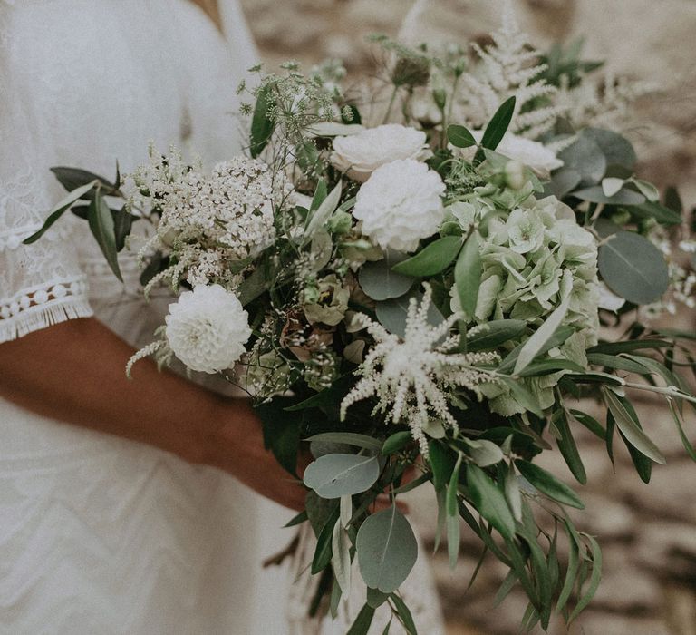 Bride in Grace Loves Lace bardot wedding dress holding white and green bridal bouquet at Isle of Wight wedding with macrame wedding decor