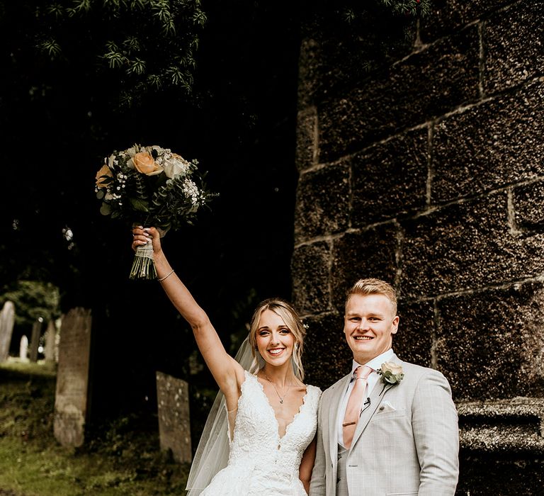 Groom in grey wedding suit with bride in lace wedding dress