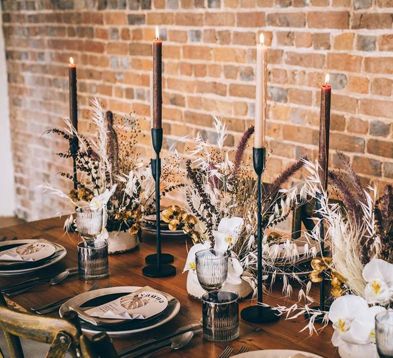 boho luxe wedding table decor with black candlestick holders, taper candles dried flowers and fresh orchids 