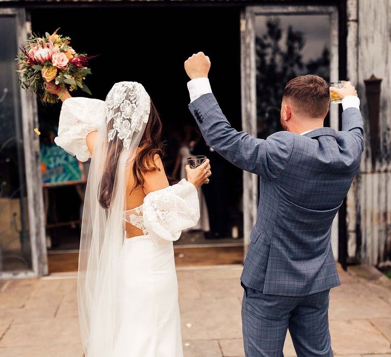 Bride & groom celebrate after ceremony as they hold cocktails 