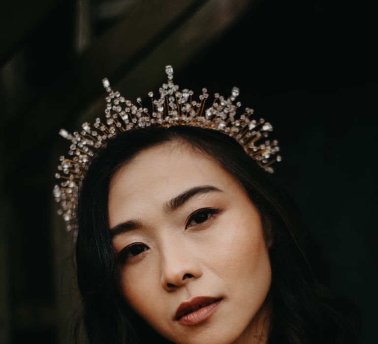 Bride with short hair and bejewelled bridal headpiece holds tropical bridal bouquet as she stands in doorway