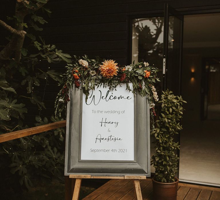 Framed monochrome welcome wedding sign with orange flower decor