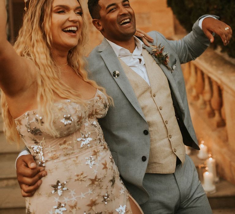 Bride & groom celebrate as they hold champagne bottle and smile