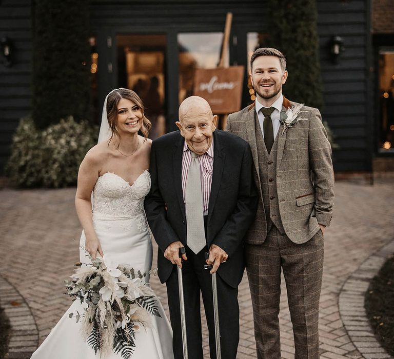 Bride and groom smile with wedding guest