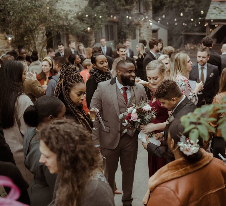 Wedding guests stand outdoors on wedding day