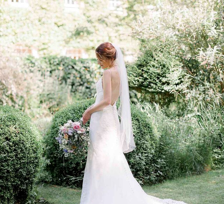 Bride wears lace wedding gown complete with V shaped open back