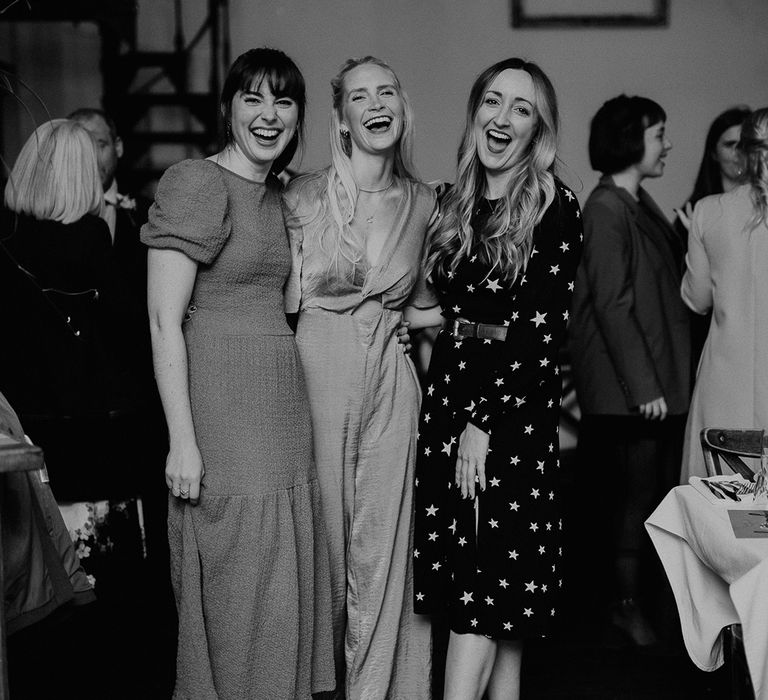 Wedding guests smile and laugh with one another on wedding day