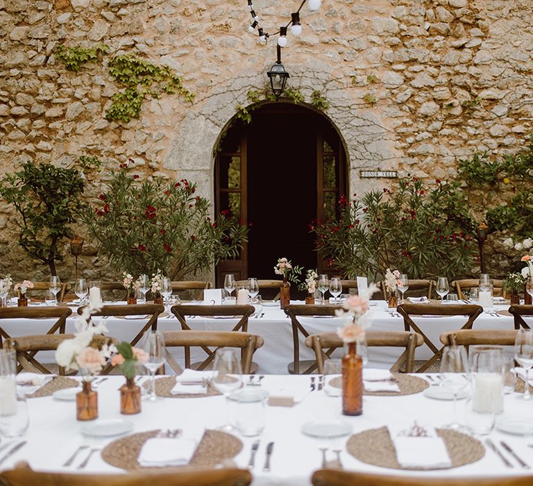 Tables set for the guests with pink and white flowers 