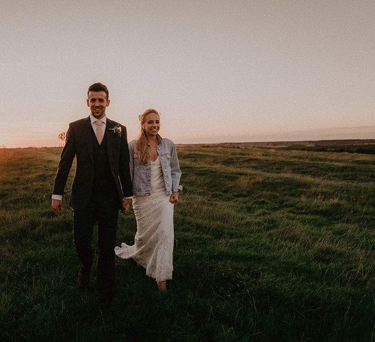 Bride and groom walk in the stunning scenery around Primrose Hill with bride wearing personalised denim jacket