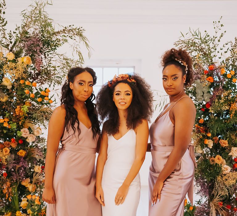 Bridal party with bride in a white satin slip wedding dress and bridesmaids in rose satin bridesmaid dresses 