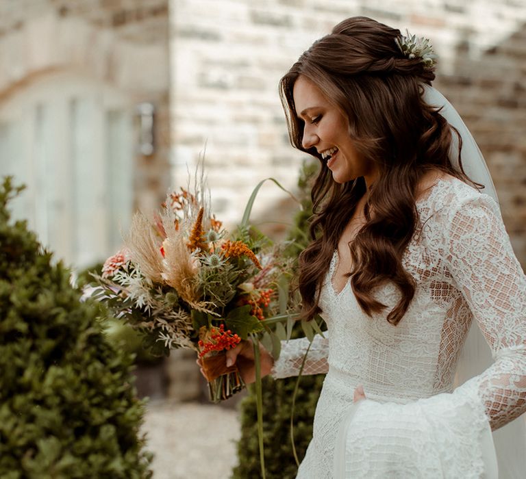 Bride in Maggie Sottero lace wedding dress with curls half up half down brown hair and veil with autumnal bouquet