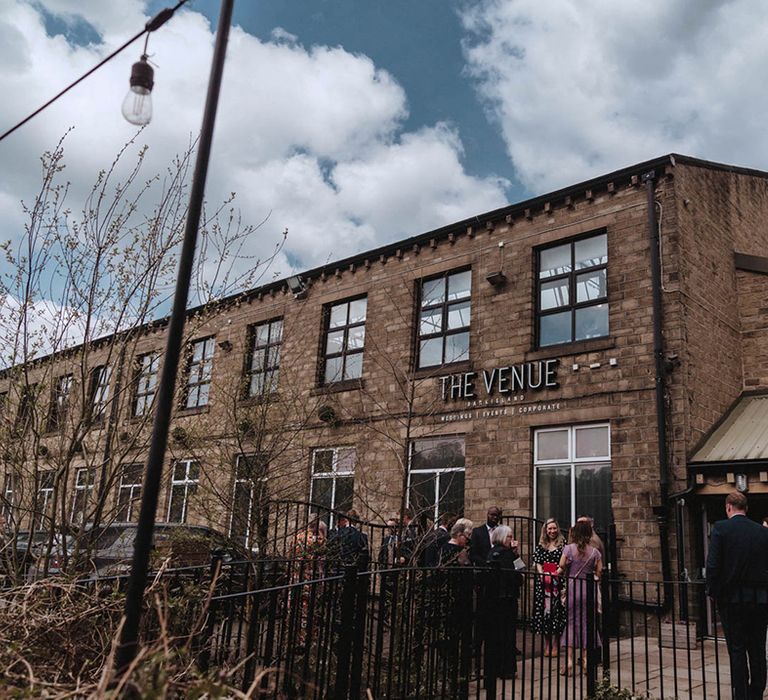 Wedding guests socialise outside of Bowers Mill industrial wedding venue