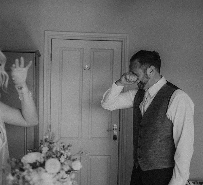 Father of the bride wipes his eyes as he cries seeing the bride for the first time 