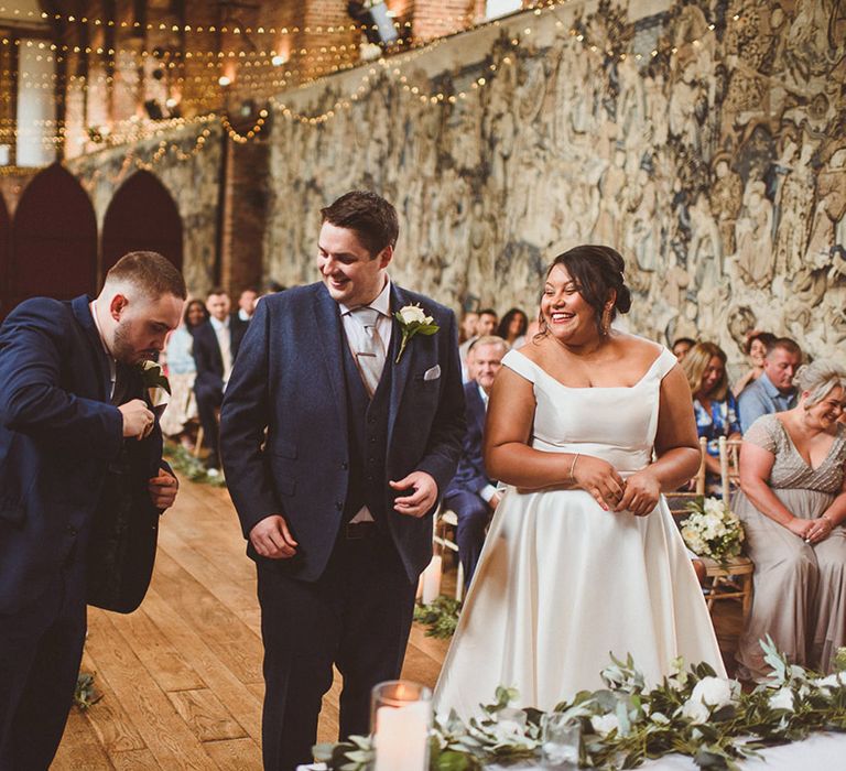 Best man gets out the rings from his suit jacket pocket during the wedding ceremony decorated with fairy lights 