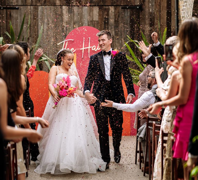 Bride & groom walk through colourful confetti after outdoor wedding ceremony at the 100 Barrington in Brixton 