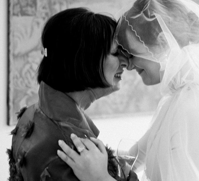 Bride wearing hood styled cathedral veil becomes emotional with family member on the morning of her wedding day 