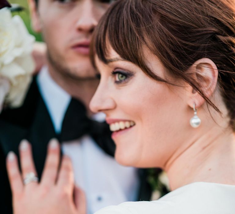 Bride wears pearl drop earrings and her hair in low-bun on her wedding day