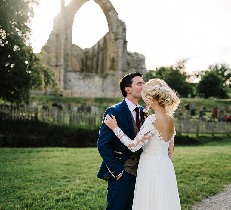 Bride wears her blonde hair in intricate curled hair style complete with embellished hair accessories 