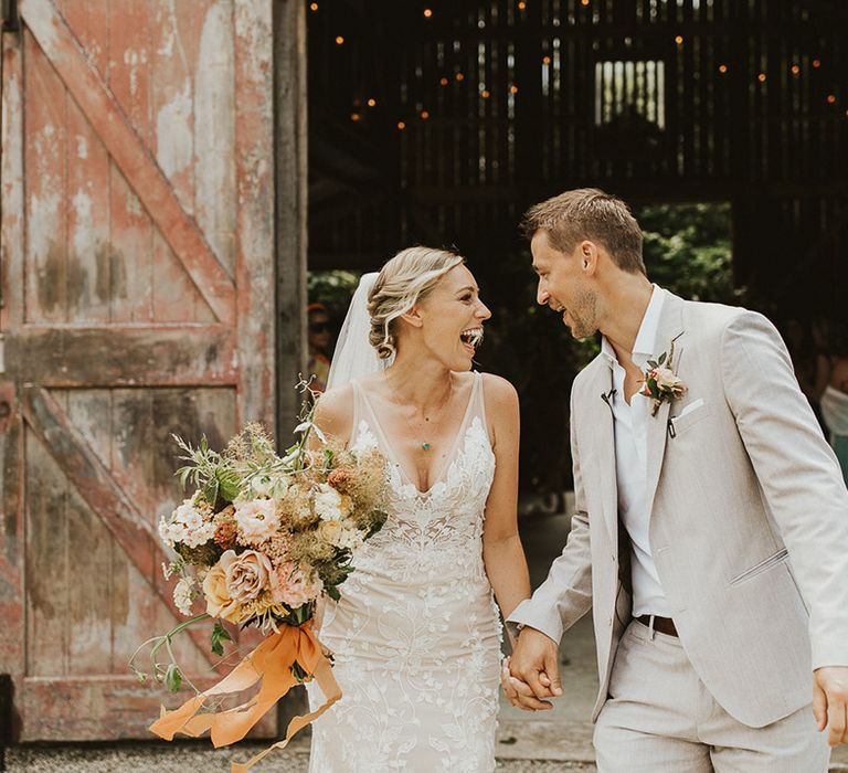 Bride and groom smile at each other as they exit their ceremony as husband and wife 