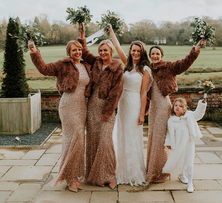 Bridesmaids in gold dresses with fur cover ups for a Christmas wedding 