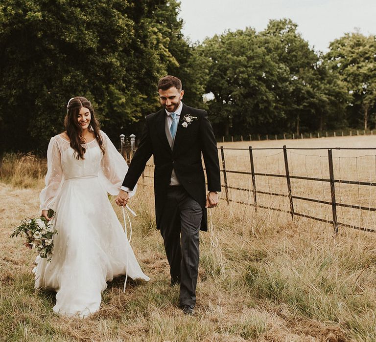 Bride in a Phillipa Lepley wedding dress walking with the groom in a morning suit with a pale blue tie