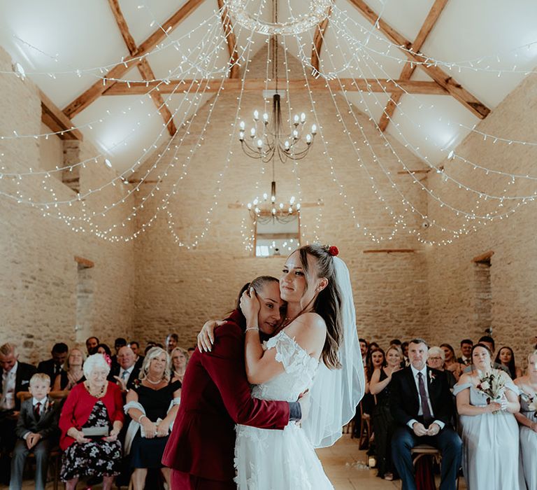 Brides share an intimate embrace as they stand at the altar at Kingscote Barn rustic wedding venue 