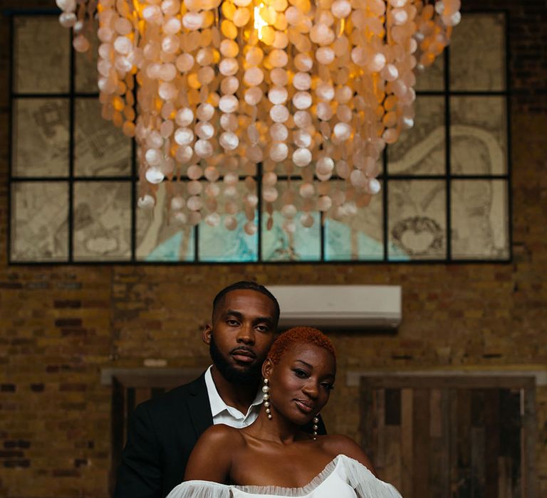 Bride in off shoulder wedding dress with dramatic puff lace sleeves and groom in stylish black suit standing in front of minimal wedding tablescape with black and white table decorations