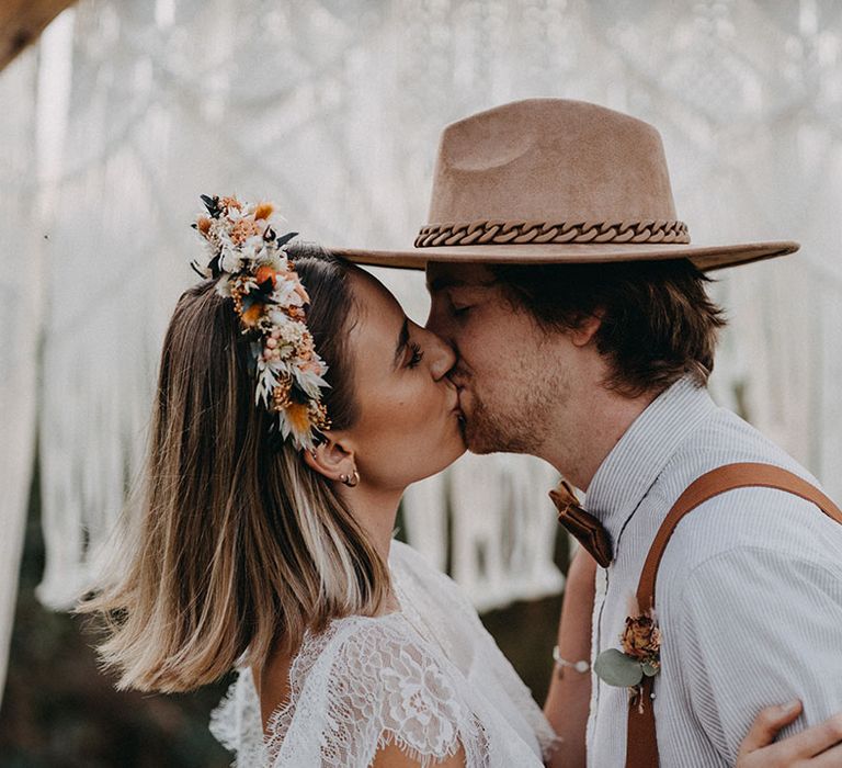 Bride in a boho wedding dress with a dried flower headband with the groom in a striped shirt and brown hat 