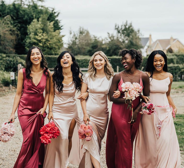 Bridesmaids all wear satin dress in different shades of pink 