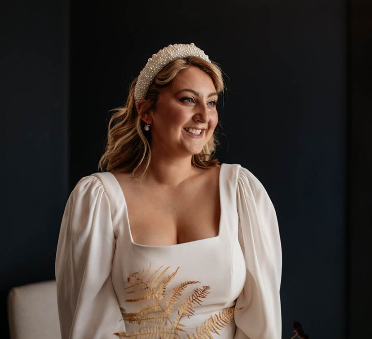 Bride wearing a puff long sleeve wedding dress with square neckline with chunky pearl headband and pearl earrings 