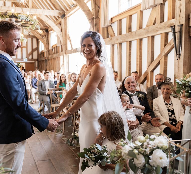 Bride in Grace Loves Lace wedding dress holds her grooms hands during civil ceremony at barn wedding venue 