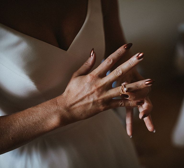 Bride wears pearl ring with gold band and bronzed nails