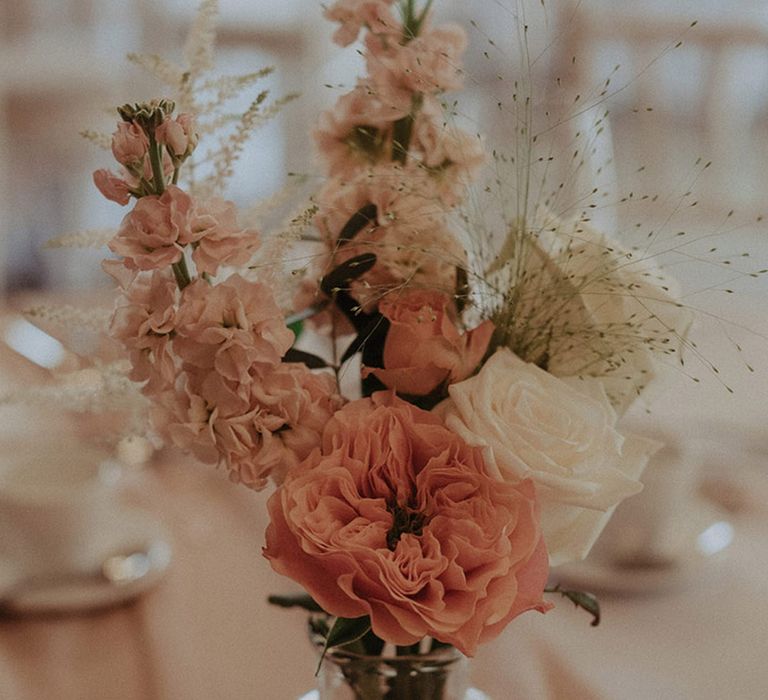 Peach, pink, and white wedding flower arrangements for the table decor with roses and peonies at rustic luxe wedding day 