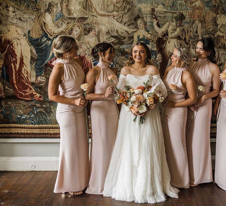 Bridesmaids in matching halter neck pink bridesmaid dresses with the bride in her whimsical wedding dress by Watters 