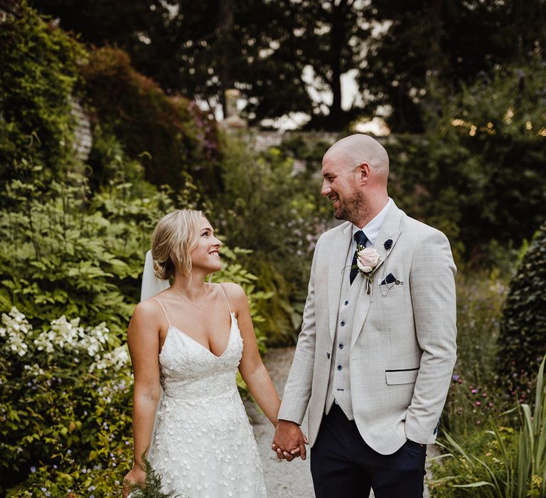 Bride in Lana dress by Alexandra Grecco smiling up at the groom in a light grey suit 