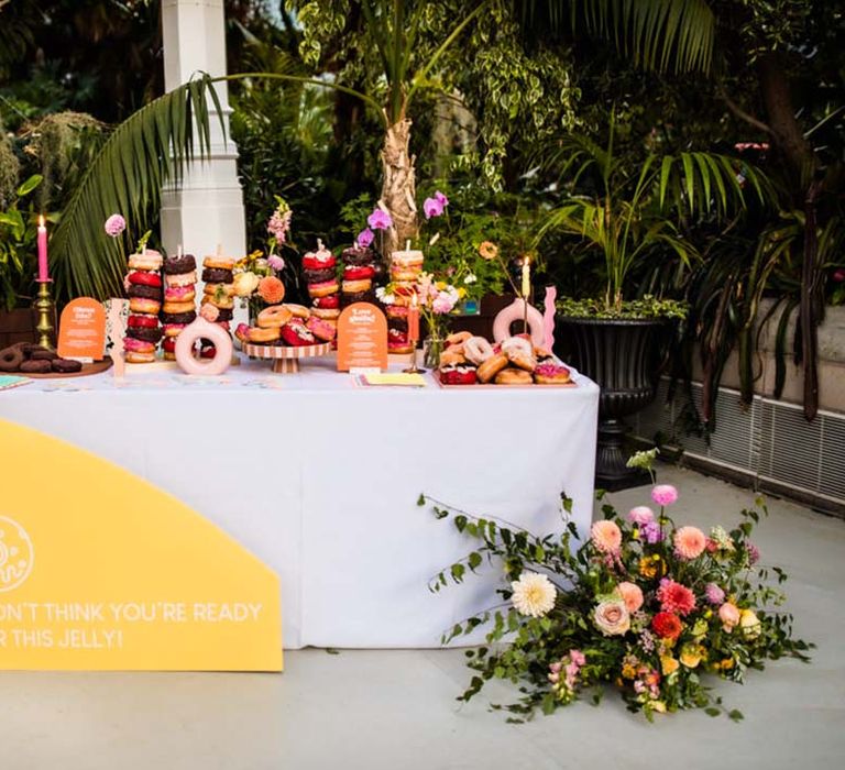 Wedding dessert table filled with doughnuts with vibrant wedding flowers and lemon yellow wedding signage for glasshouse wedding 