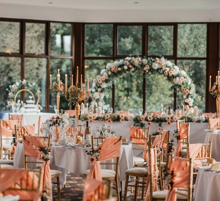 Golden wedding candelabras with pink chair back decor and white wedding tablescapes at Bron Eifion wedding venue