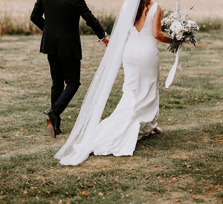 Bride in Made With Love wedding dress with long wedding veil with the groom