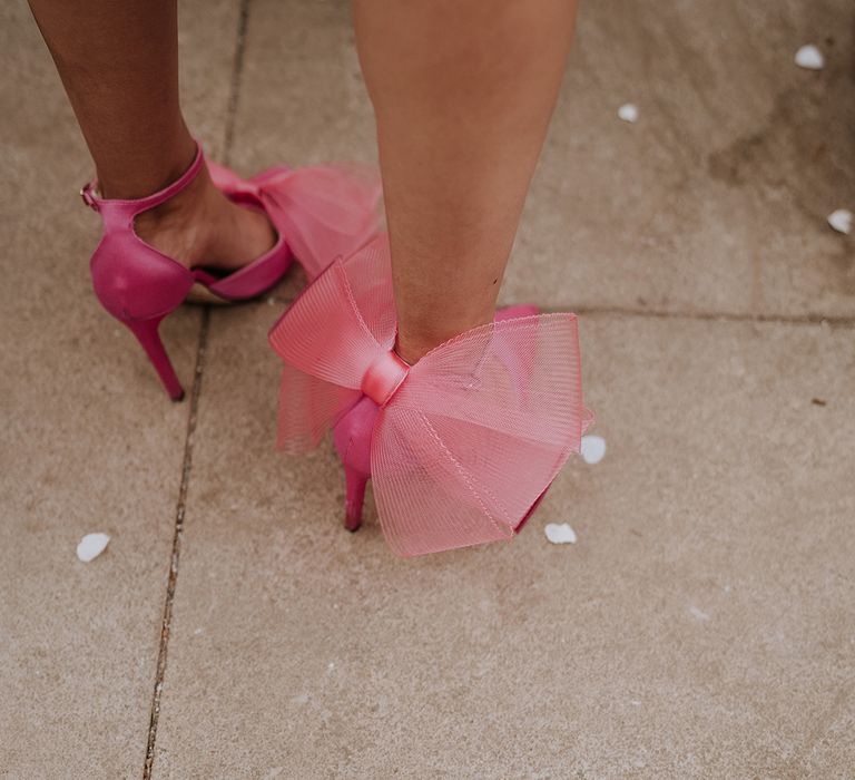 Wedding guest wearing pink bow wedding high heels for red and pink wedding theme 